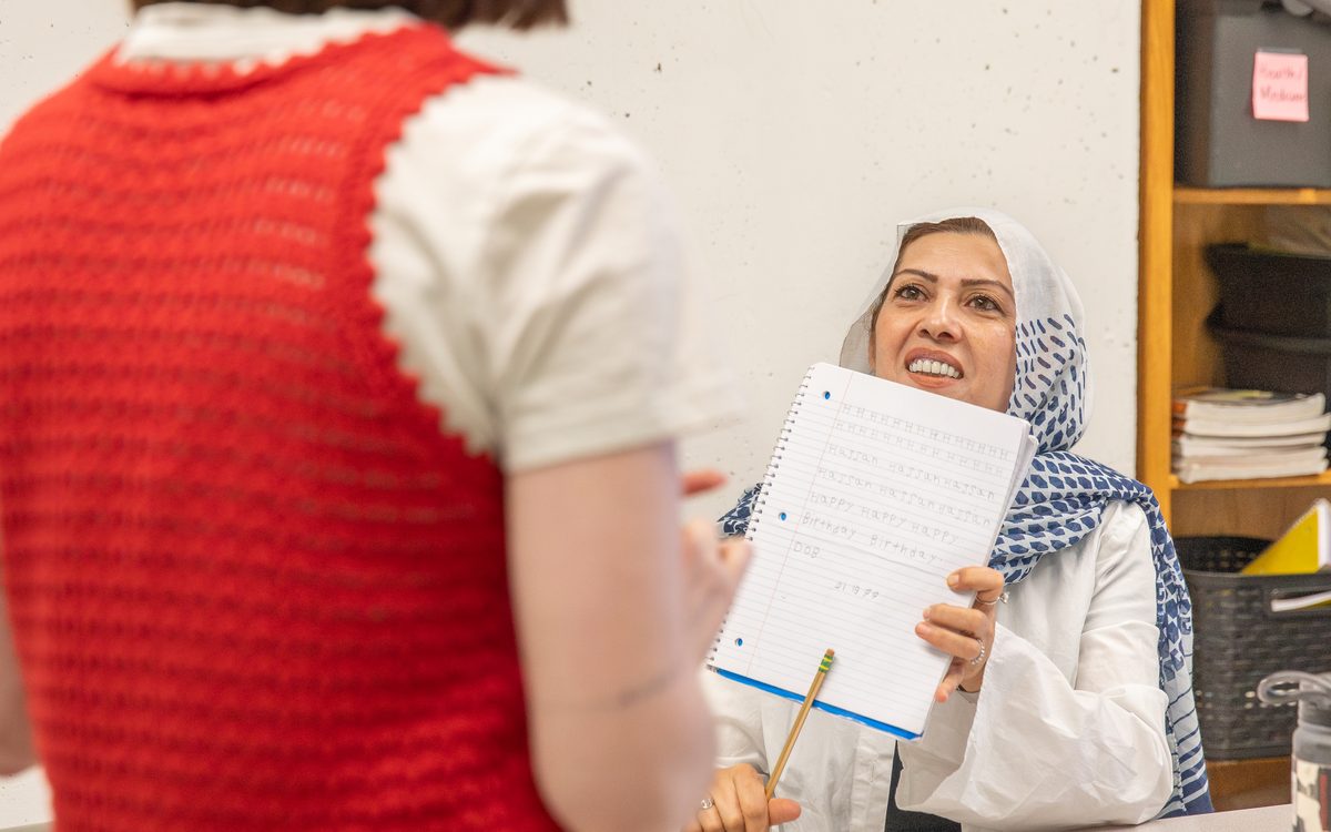 A volunteer teacher and a student reviewing her notebook at the English Learning Center